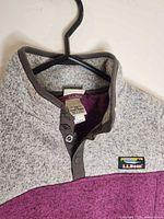 Close-up of collar, snap placket, logo tag and interior label