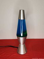 Full view of lava lamp, silver base and cap, blue liquid with yellow-green wax visible