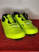Oblique view of both neon yellow cycling shoes showing uppers, dials, Velcro straps, and cleats