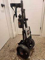 Cart folded upright showing wheels, bottle holder and scorecard holder