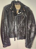 Front view of black leather motorcycle jacket on hanger