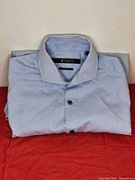 Folded Tiger of Sweden light blue shirt on red surface