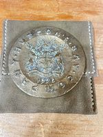 Medal resting on suede pouch showing obverse design and patina