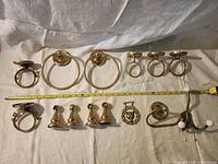 Full layout of all brass bathroom hardware items with tape measure for scale