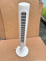 Full view of white Honeywell tower fan standing on round base
