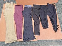 Six pairs laid flat: khaki, burgundy, charcoal, three black leggings