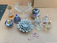 Group shot showing all perfume bottles, candlestick, ceramic dish, jar and dragonfly