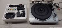 Turntable beside styrofoam tray with Denon dock and accessories