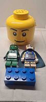 Group shot of yellow storage head, two minifigure alarm clocks, and blue brick alarm clock