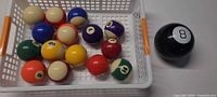 Basket holding 15 miniature billiard balls beside Magic 8 Ball