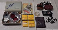 Group shot of flash, reflector, Kodak boxes, Leica brochure, filter, photoguide, light meter and leather pouches