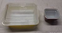 Top view of yellow rectangular Pyrex refrigerator dish with clear lid and smaller brown dish with lid