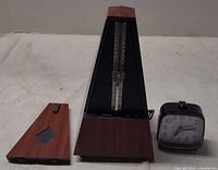 Metronome with cover removed alongside alarm clock