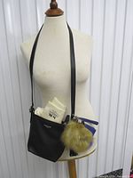 Front view of black Coach crossbody on mannequin with accessories attached
