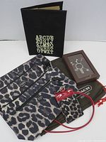 Overall view of all five items: pouch, slipcover, boxed keychain, ID lanyard, dust bag