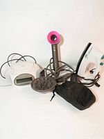Lot overview showing Dyson hair dryer, diffuser, Sony clock radio, Black & Decker iron, pouch