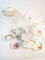 Group shot showing all china pieces including tureen, plates, cups, bowls and shaker