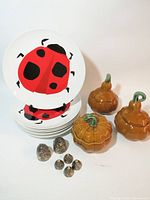 Stack of ladybug plates, three pumpkin covered dishes, six beehive pieces