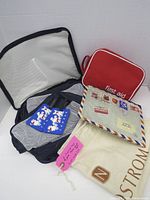 All items displayed: navy packing cube open, red first aid pouch, blue luggage tags, airmail pouch, cream Nordstrom dust bag