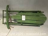 Full view of folded antique green sled showing deck, runners, and rope