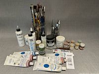 Full lot showing brushes in jars, palette knives, Golden mediums, paint tubes and pigment jars