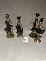 Group shot of four bronze-tone African female figurines on grey backdrop