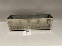 Rectangular perforated metal candle holder on neutral backdrop