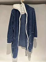 Full view of blue sherpa-lined hooded robe on hanger