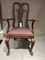 Front view of wood armchair showing antiqued burgundy finish and upholstered seat