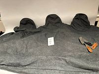 Full view of dark grey rear seat cover with three headrest shapes and strap visible