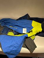 Pile of assorted dog jackets showing colors and Hurtta size 56 tag