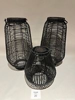 Three black metal wire solar lanterns, two tall and one shorter