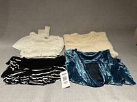 Group shot of all four garments folded: white Rodier top, cream sweater, blue top and skirt