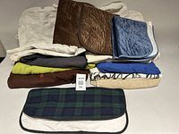 Stacked assortment of dog blankets towels and pads