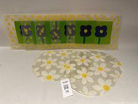 Group of plastic placemats showing rectangular flower design and oval daisy design