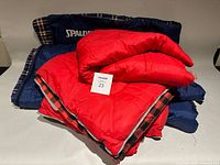 Blue Spalding and red sleeping bags folded together