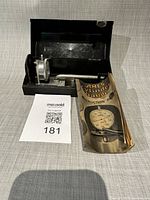 kit in open metal case with dial indicator, handle, rods, manual