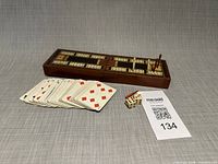 cribbage board closed, playing cards spread, two dice visible