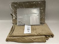 Folded olive-green velvet SANELA curtain panels with product insert showing size and care symbols