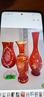 Front view of three red glass vases showing designs and size comparison with ruler