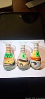 Front view of three glass sand art bottles showing desert scenes