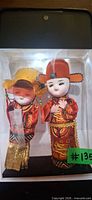 Front view of the two Chinese wedding dolls inside clear display box