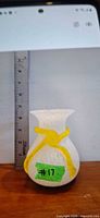 Full view of vase beside ruler showing approx. 5 in. height, displaying white splatter design and yellow ribbon