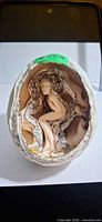 Egg opened showing carved female figure inside layered interior
