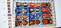 Top view of twelve Hot Wheels cars in tray showing colour variations