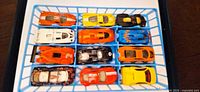 Twelve Hot Wheels cars arranged in blue compartment tray