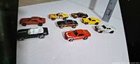 Eight loose Hot Wheels Camaro cars displayed on white surface with ruler for scale