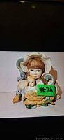 Front view of Jan Hagara "Jamie" figurine showing girl with bonnet, doll and ducks