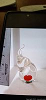 Front view of clear glass elephant paperweight with red heart and ruler showing height