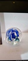 front view showing blue flower and bubbles inside clear glass sphere